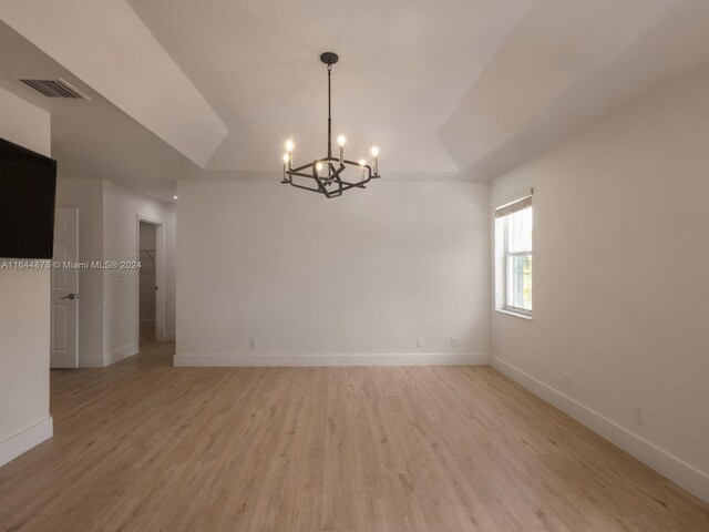 spare room featuring light hardwood / wood-style floors and a chandelier