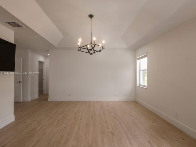 spare room with light wood-type flooring and an inviting chandelier