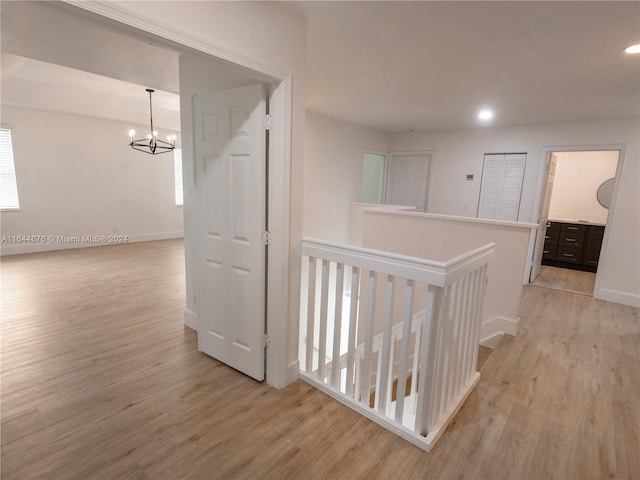 corridor featuring a notable chandelier and light hardwood / wood-style flooring