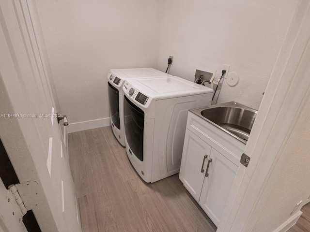 laundry area with sink, light hardwood / wood-style floors, separate washer and dryer, and cabinets