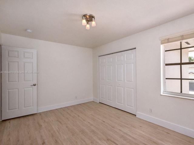 unfurnished bedroom with light wood-type flooring and a closet