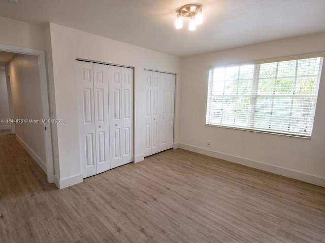 unfurnished bedroom with hardwood / wood-style flooring and multiple closets