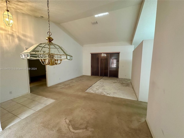 entrance foyer with a textured ceiling, lofted ceiling, a chandelier, and light carpet