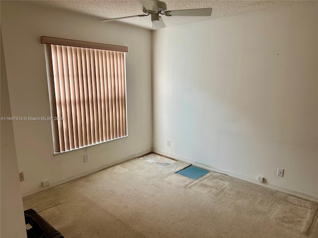 carpeted spare room featuring ceiling fan and a textured ceiling