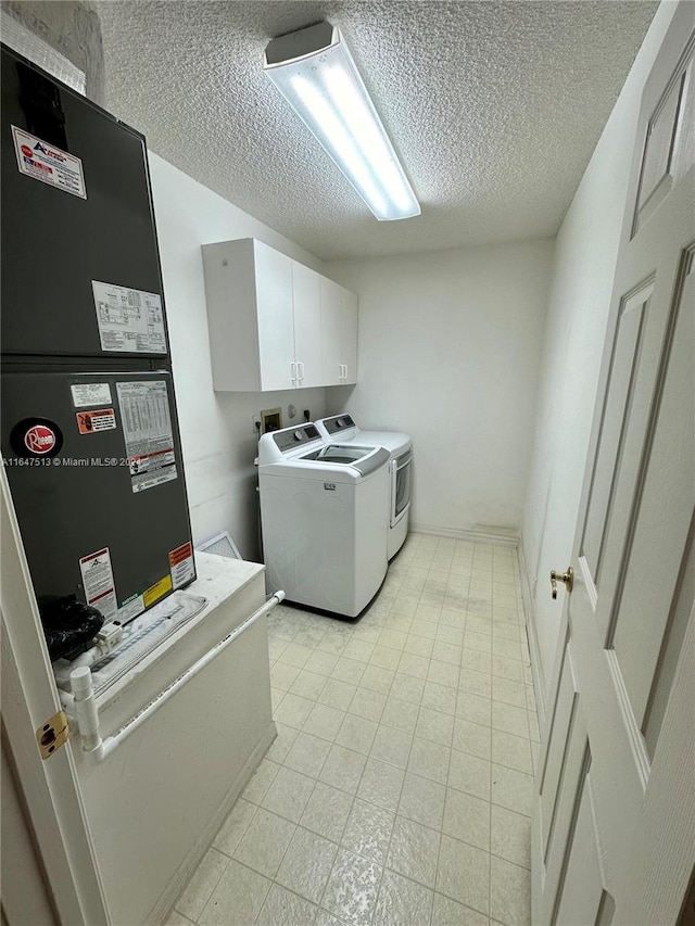 laundry room with cabinets, a textured ceiling, heating unit, light tile patterned floors, and independent washer and dryer