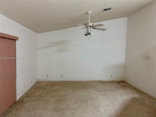 carpeted empty room featuring ceiling fan, vaulted ceiling, and a textured ceiling