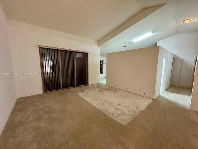 spare room with light carpet and vaulted ceiling