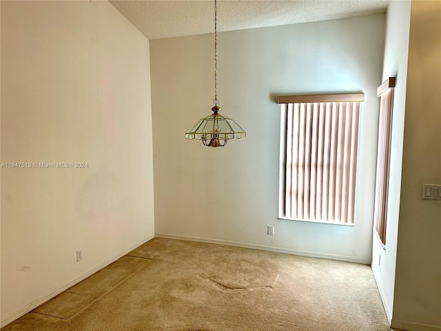 carpeted empty room featuring a textured ceiling and vaulted ceiling