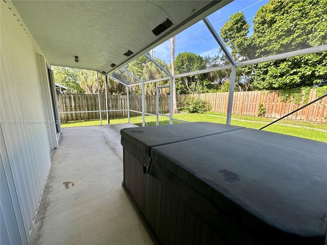 view of patio with glass enclosure and a hot tub