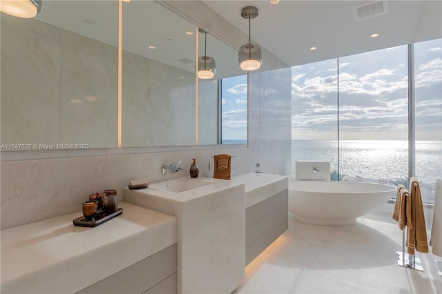 full bath featuring a water view, visible vents, a wealth of natural light, and a freestanding bath