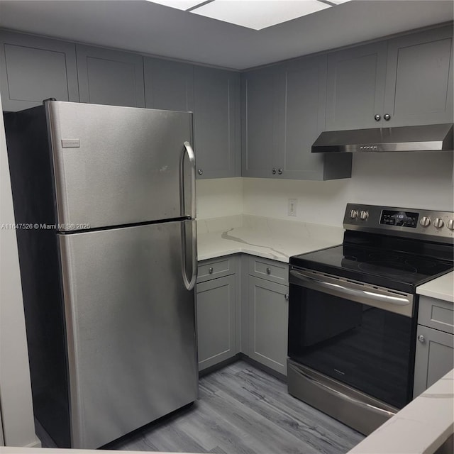 kitchen with gray cabinetry, appliances with stainless steel finishes, light wood-style flooring, and under cabinet range hood