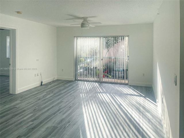 empty room with a ceiling fan, a textured ceiling, baseboards, and wood finished floors