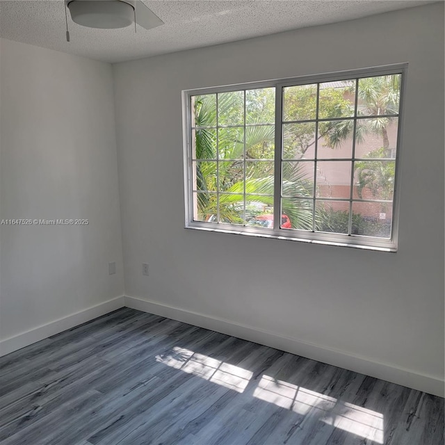 empty room featuring plenty of natural light, a textured ceiling, and baseboards