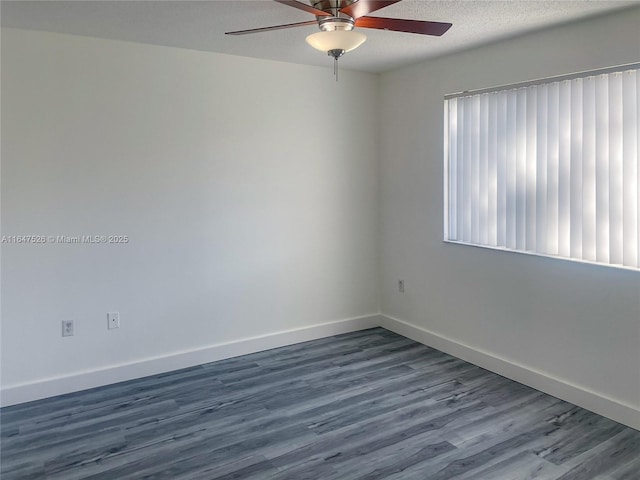 empty room with baseboards, dark wood finished floors, and a textured ceiling