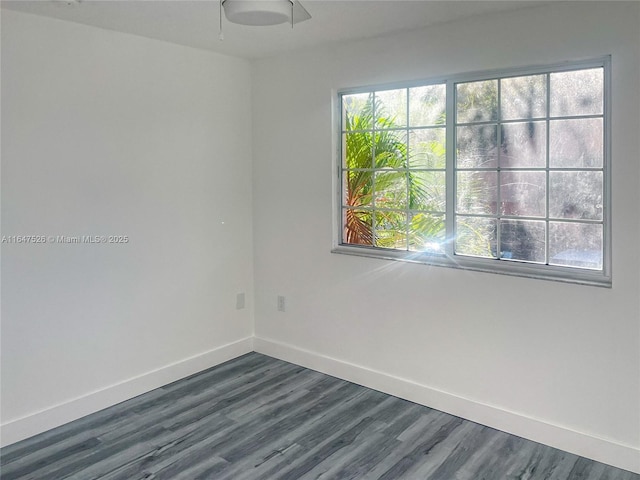 spare room featuring baseboards and dark wood finished floors