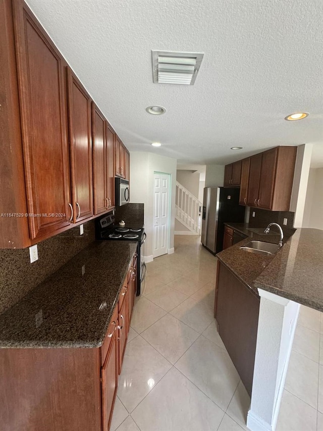 kitchen featuring appliances with stainless steel finishes, kitchen peninsula, sink, and dark stone counters