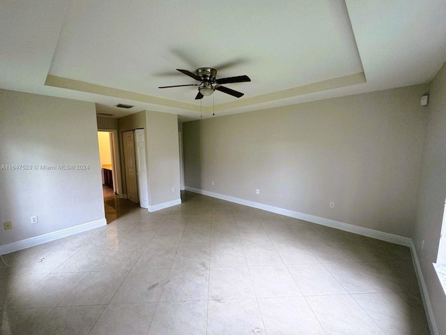 empty room featuring a raised ceiling and ceiling fan