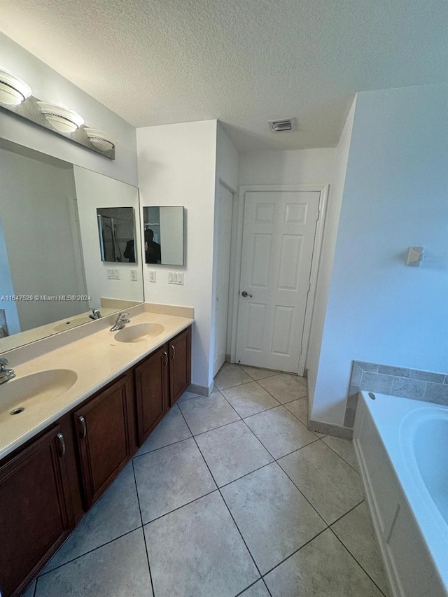 bathroom featuring a tub to relax in, vanity, tile patterned flooring, and a textured ceiling