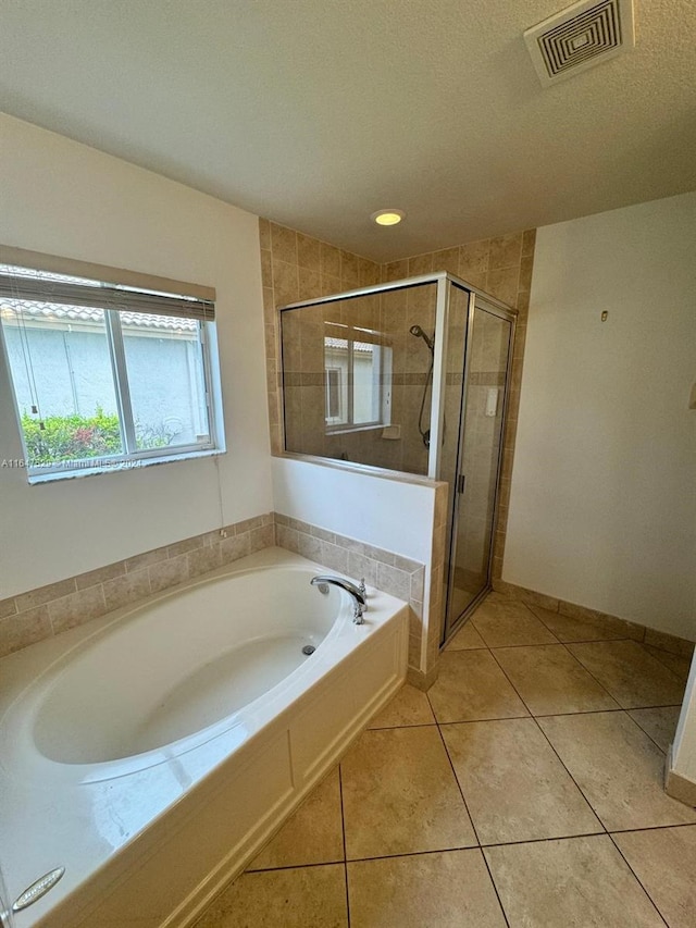 bathroom with plus walk in shower, a textured ceiling, and tile patterned floors