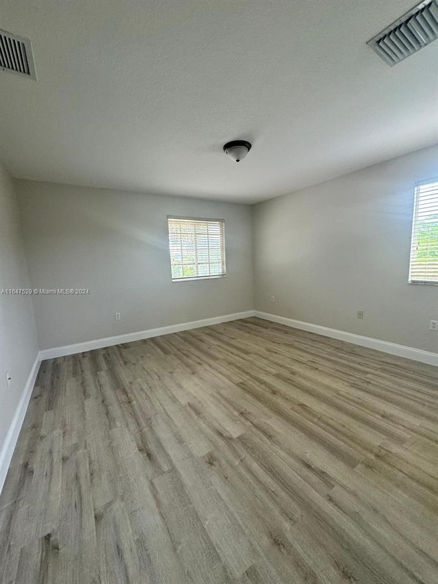 unfurnished room with a wealth of natural light, light wood-type flooring, and a textured ceiling