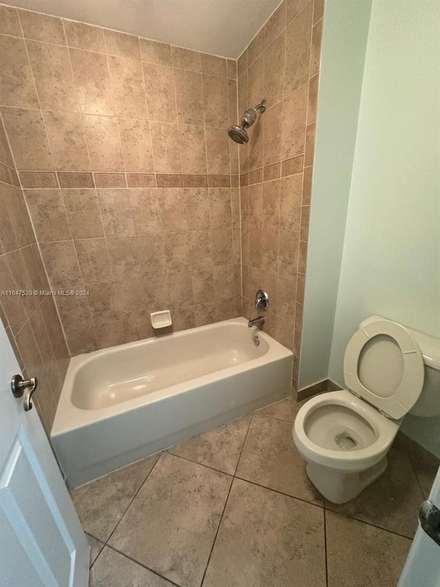 bathroom with tiled shower / bath, toilet, and tile patterned flooring