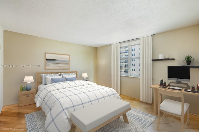 bedroom with a textured ceiling and light hardwood / wood-style flooring