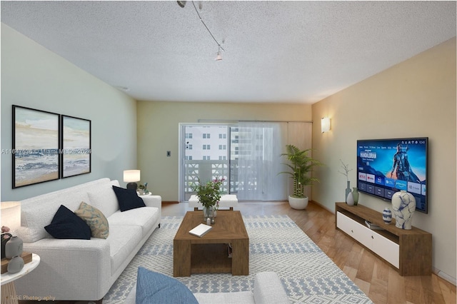 living room with a textured ceiling, baseboards, and wood finished floors