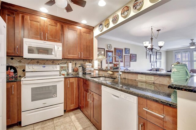 kitchen featuring dark stone counters, ceiling fan with notable chandelier, white appliances, tasteful backsplash, and kitchen peninsula