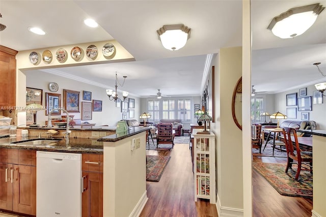 kitchen with white dishwasher, dark stone countertops, ceiling fan with notable chandelier, and hardwood / wood-style flooring