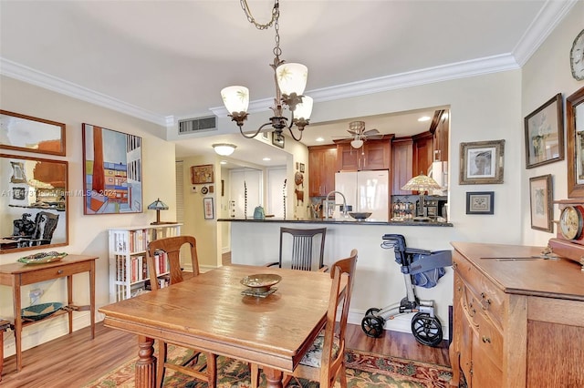 dining room with an inviting chandelier, light hardwood / wood-style floors, and ornamental molding