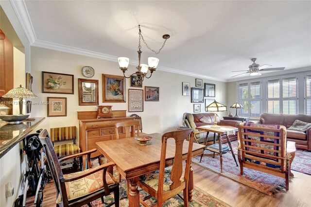 dining space with light wood-type flooring, ornamental molding, and ceiling fan with notable chandelier