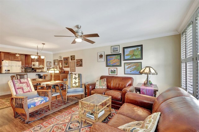 living room with light hardwood / wood-style flooring, ornamental molding, and ceiling fan with notable chandelier