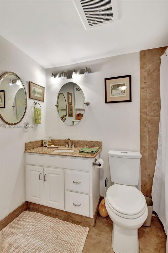 bathroom featuring vanity, toilet, a shower with curtain, and tile patterned floors