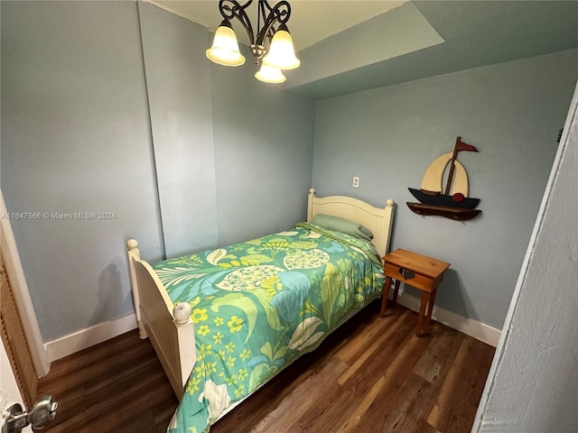 bedroom with wood-type flooring and an inviting chandelier