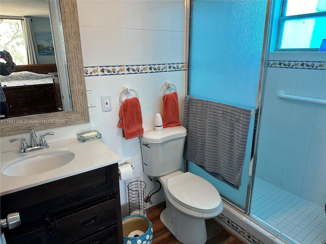 bathroom with wood-type flooring, an enclosed shower, vanity, tile walls, and toilet