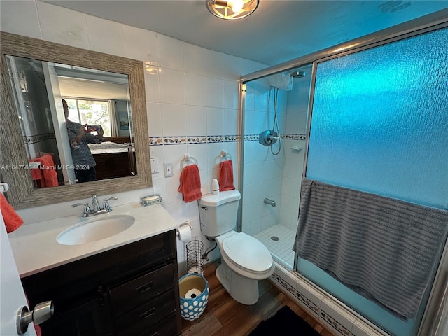 bathroom featuring toilet, an enclosed shower, vanity, tile walls, and hardwood / wood-style flooring