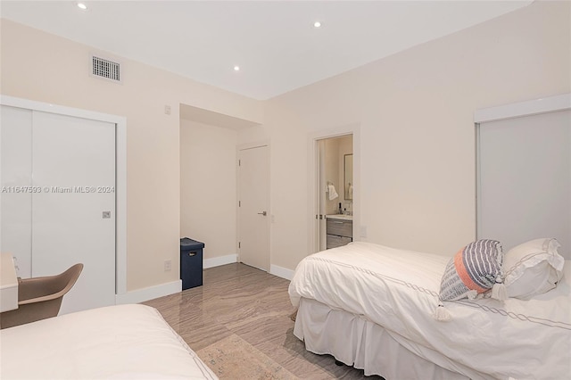 bedroom featuring light tile patterned flooring, connected bathroom, and a closet