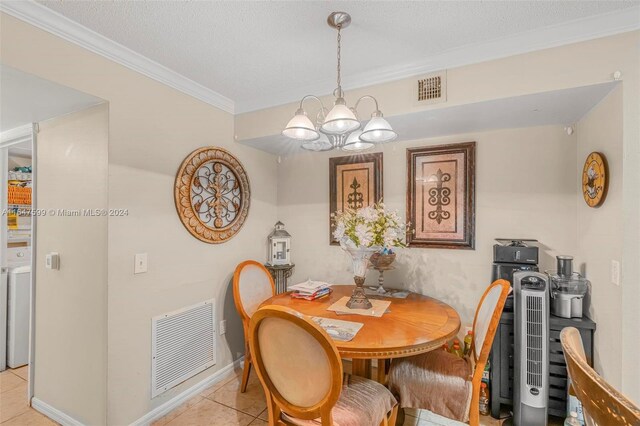 tiled dining space featuring a textured ceiling, a chandelier, ornamental molding, and washer / clothes dryer