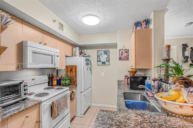 kitchen featuring sink, a textured ceiling, white appliances, and light tile patterned floors