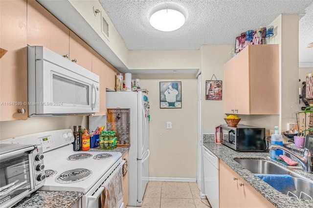 kitchen featuring sink, white appliances, a textured ceiling, and light tile patterned floors