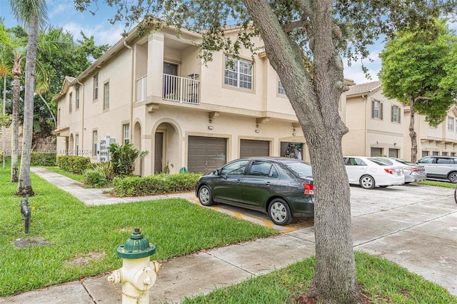 view of front of property featuring a balcony, a front lawn, and a garage