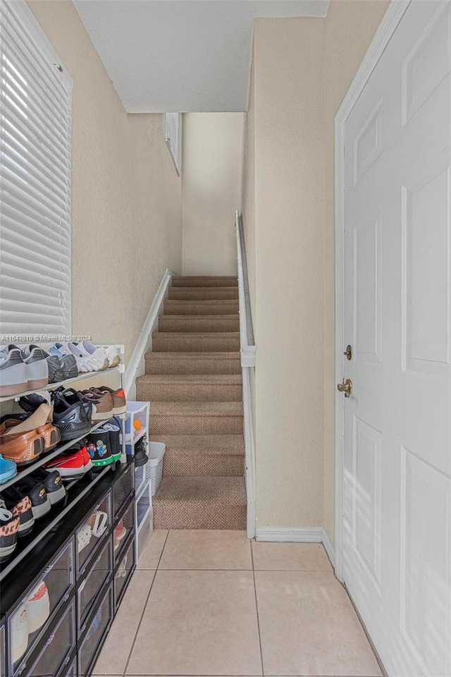 stairway with tile patterned flooring and baseboards