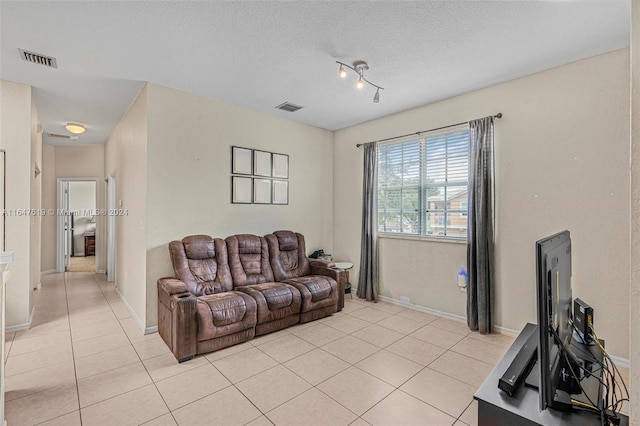 living area featuring light tile patterned floors, a textured ceiling, visible vents, and baseboards