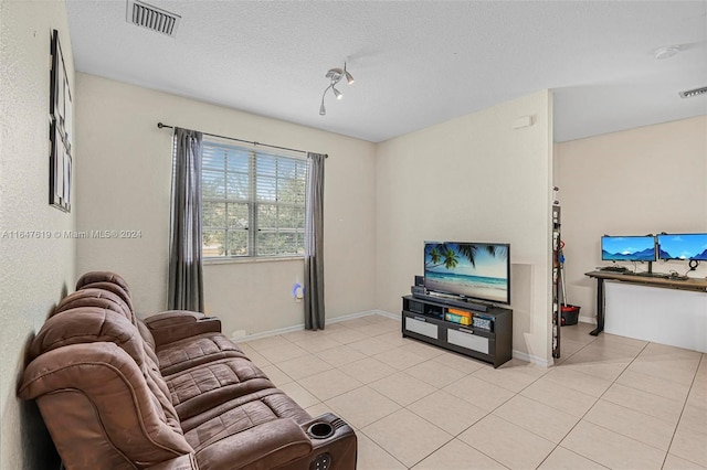 living room with light tile patterned floors, a textured ceiling, visible vents, and baseboards