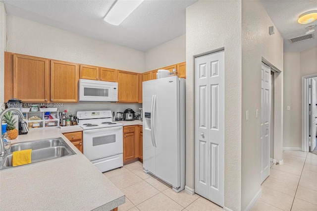 kitchen featuring light countertops, white appliances, light tile patterned flooring, and a sink