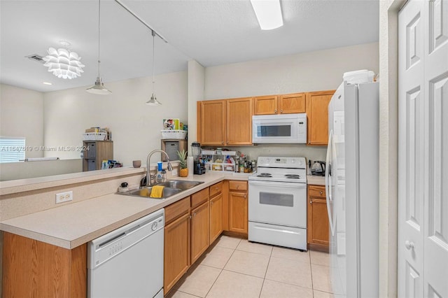 kitchen with light tile patterned floors, light countertops, a sink, white appliances, and a peninsula