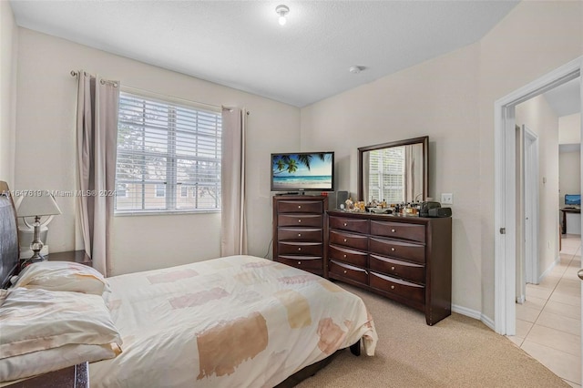 bedroom with light carpet, baseboards, and light tile patterned flooring