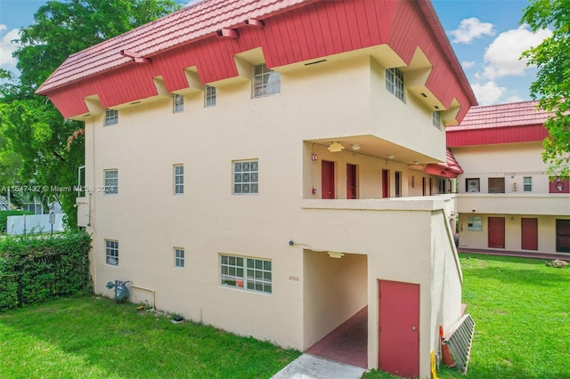 exterior space featuring a yard, a tile roof, and stucco siding