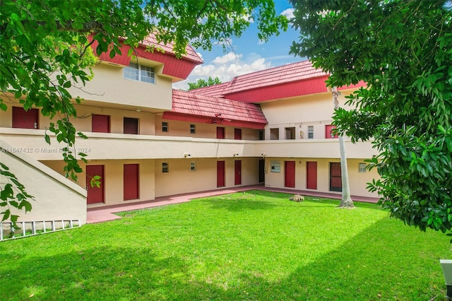 rear view of property featuring a balcony and a yard