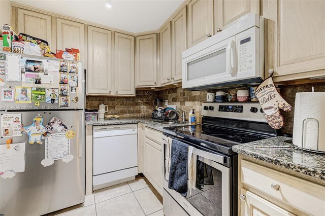 kitchen with light brown cabinets, tasteful backsplash, light tile patterned floors, dark stone countertops, and stainless steel appliances